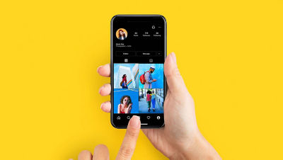 一只手握着黄色背景上的手机。 屏幕显示社交媒体应用程序中的四张蓝色背景图像。